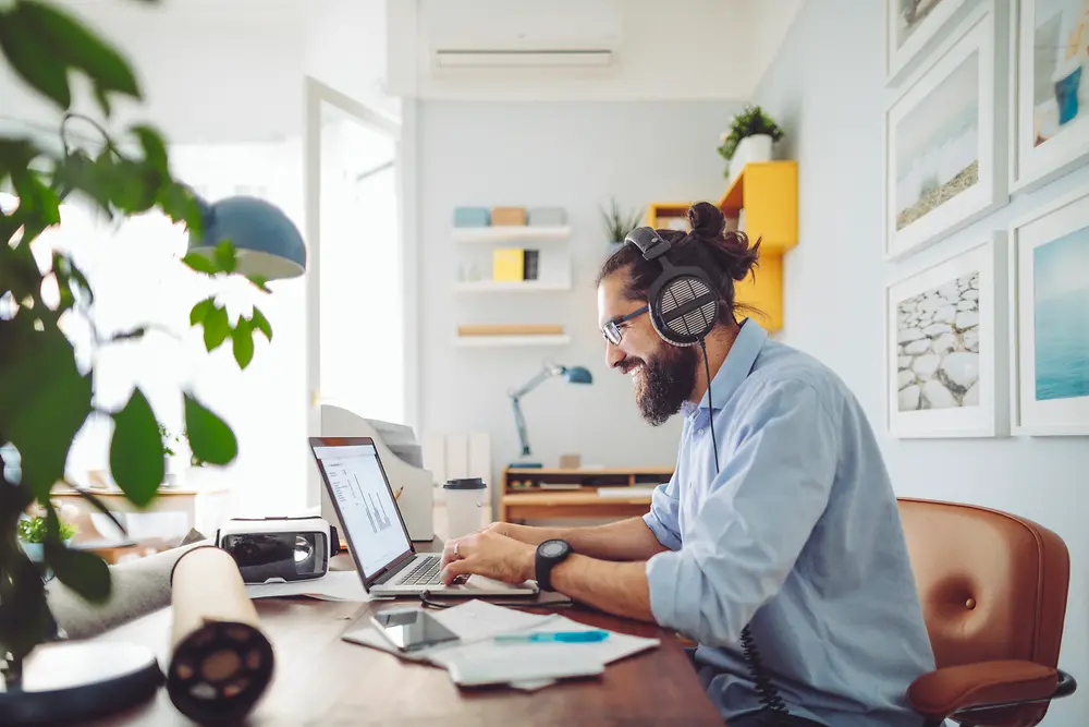Mand med headset sidder ved skrivebordet og arbejder